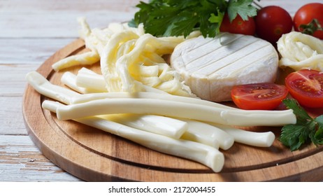 Camembert With String Cheese Or Cheese Whip - Salty Snack Cheese With Cherry Tomatoes And Herbs On Chopping Board. 