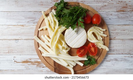 Camembert With String Cheese Or Cheese Whip - Salty Snack Cheese With Cherry Tomatoes And Herbs On Chopping Board. 