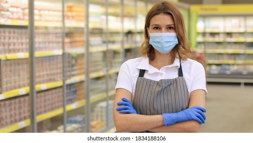 Camera Approaching Pretty Woman Supermarket Assistant Posing Indoors. Close Up Portrait Of Caucasian Beautiful Female Employee In Mask Looking At Camera While Standing In Grocery Store. Job Concept