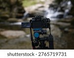 A camera capturing a waterfall scene in a natural stream environment, showcasing long exposure photography technique and composition.