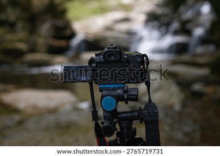 A camera capturing a waterfall scene in a natural stream environment, showcasing long exposure photography technique and composition.