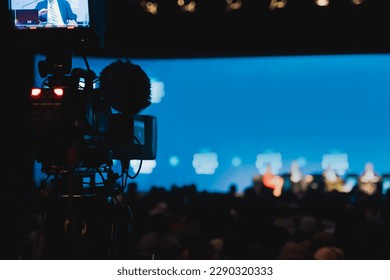 The camera connected to the live broadcast vehicle has its tally light on while participants are speaking at an international conference being broadcasted live on a news channel.
