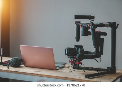 Camera DSLR professional Gimbal stabilizer production and laptopon the table gear of Vlog or Blogger content creator freelance