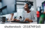 Camera focus on African American woman wearing headset during online consultation with customer. Hardworking manager noting information of conversation on computer. Client service concept.