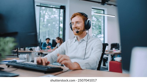 Camera focus on handsome Caucasian male sitting at desk. Putting on wired headphones with microphone. Beginning conversation with client or company. Technical support department. Smiling with joy. - Powered by Shutterstock