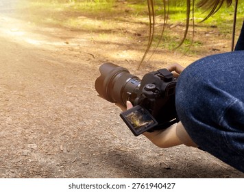 Camera held low capturing ground perspective of forest path surface. Outdoor photography scene shows device used for shooting natural environment. Lifestyle concept of exploration, hobby, travel,