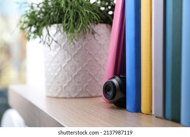 Camera Hidden Between Books On Wooden Shelf Indoors, Closeup. Space For Text