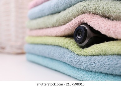 Camera Hidden Between Folded Towels Indoors, Closeup. Space For Text