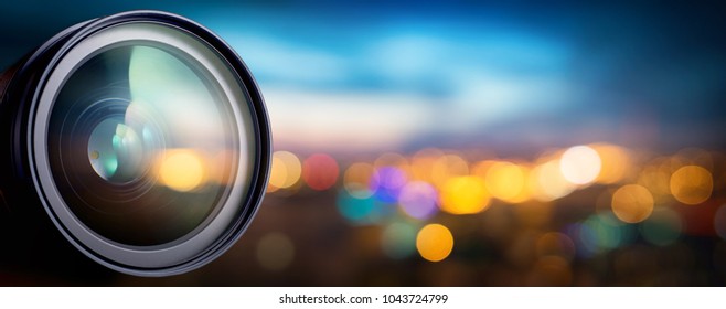 Camera lens with lense reflections on blur night city. Media and technology concept background.
