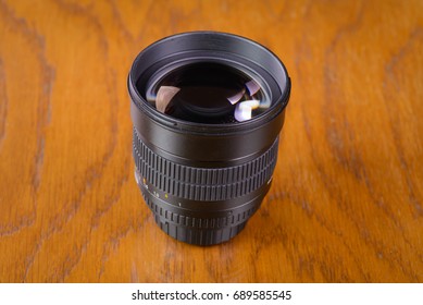 Camera lens with light reflection on a wooden table