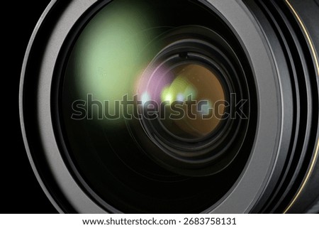 Camera lens surface reflecting light on a black background, focusing on optics and imaging.
