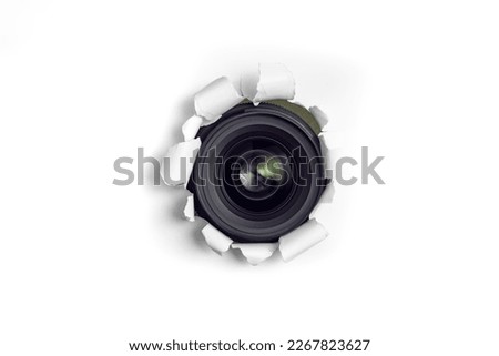 Camera lens taking pictures thru a torn hole in white paper