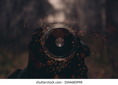 A Camera Lense In A Hand With Sparks Flying Around