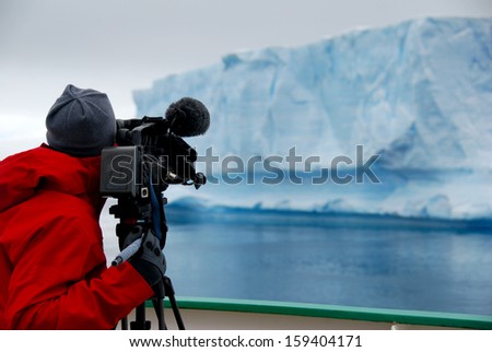 camera man filming an iceberg in antarctica