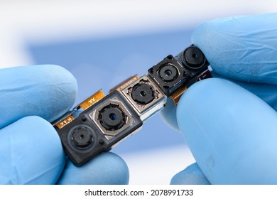 Camera modules with different sensor technology and resolution in scientist hands. Smartphone cell phone cameras research or repair concept in laboratory.