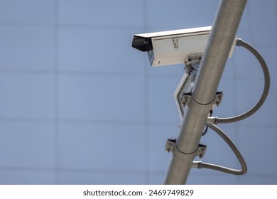 A camera is mounted on a pole. The pole is attached to a wire. The camera is pointed at the sky