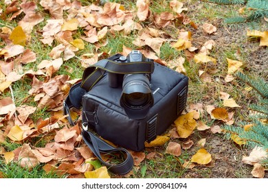 Camera on a bag among yellow leaves.