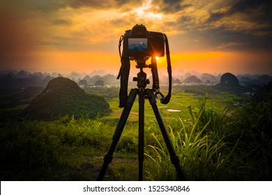 Camera on tripod and photography view camera with blurred focus landscape of sunset sunrise sun light sky cloud