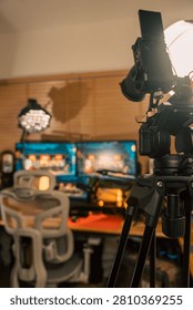 Camera on a tripod with a softbox light facing a home content creator desk and monitors