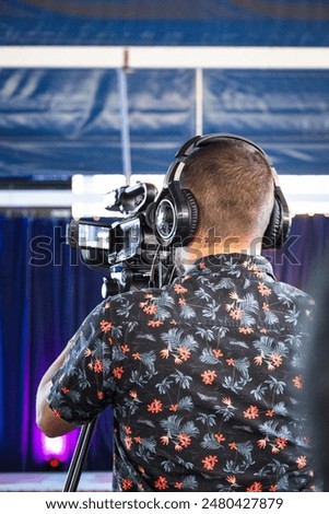 Camera operator recording a school children's performance. Recording of the children's performance. End of the school year. Young man at work. Audiovisual work. Camera. Stage. Girls on stage.