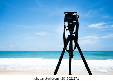 Camera set up on tripod shooting beach sea sunny day. Shooting photo wave white sand blue sky for travel trip summer. - Powered by Shutterstock