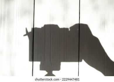 The camera stands on a tripod shadow on the wall with light from the window. abstract shape
Photo camera shadow on the wall with copy space for text.