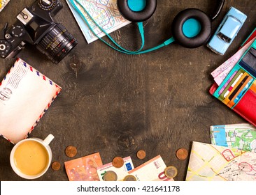 Camera, touristic maps, passport, toy car, coffee, headphones, wallet with credit cards, euro banknotes and coins on a black desk. Travel background. Tourist essentials. Plan a journey. Space for text - Powered by Shutterstock