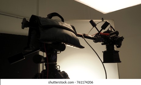 Camera and tripod with light soft box in studio production and low angle view.