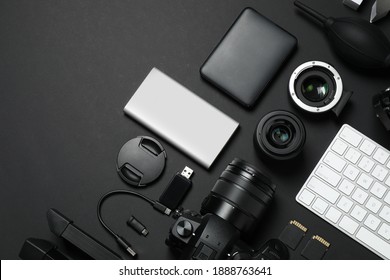 Camera, video production equipment and computer keyboard on black background, flat lay