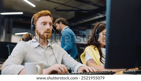 Camera view behind computer on mixed-raced workers. Busy people with headsets communicating online with customers. Call center managers answering calls and providing information. Using computers.