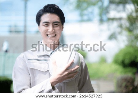 Camera view of a man in work clothes outdoors of a building reflecting blue sky Trust and confidence entrusted to us Image of construction management, etc. with helmets	