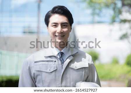 Camera view of a man in work clothes outdoors of a building reflecting blue sky Trust and confidence entrusted to us Image of construction management, etc. with helmets	