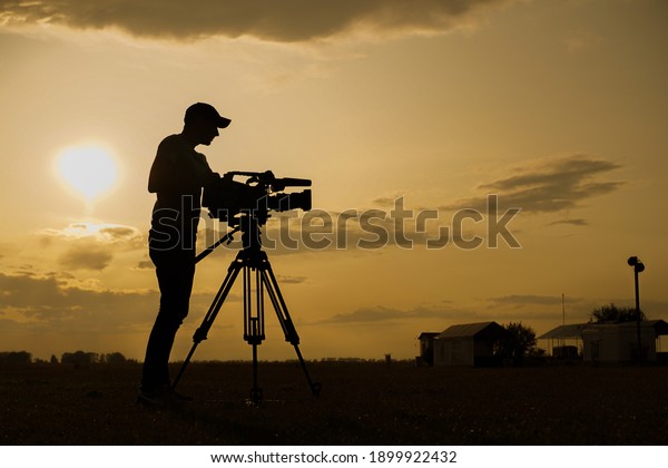 a cameraman with a camera at\
sunset behind the scenes of the filming process a\
cinematographer