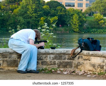 A Cameraman Filming Stock Footage Of A River.