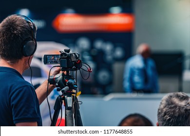 Cameraman recording male speaker wearing suit at media press conference. Live streaming concept. - Shutterstock ID 1177648855