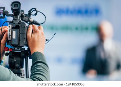 Cameraman Recording Well-dressed Male Speaker At Press Conference. Live Streaming Concept.