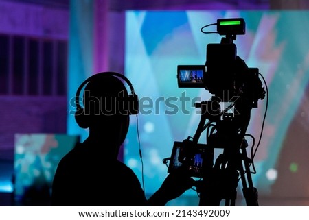 Cameraman silhouette. Professional cameraman - covering on event with a video, cameraman silhouette on live studio news. Television live streaming.