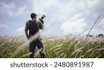  Cameraman standing holding camera in the middle of a meadow. Travel and outdoor adventure concept.