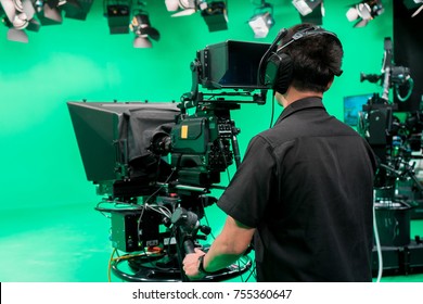 Cameraman Taking A Broadcast Camera  In Broadcast Television Virtual Green Screen Studio Room.