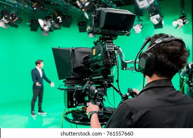 Cameraman working with announcer in broadcast television green screen studio room and professional camera.