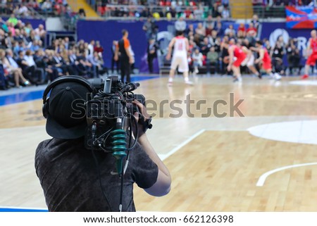 Cameraman works at basketball game in big stadium, back view Stok fotoğraf © 