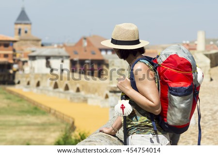 Camino de Santiago to Compostela with pilgrim woman with backpack and scallop symbol in Hospital de Orbigo village  , Leon , Spain 