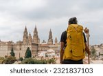 Camino de Santiago - Young hipster pilgrim ends the Way of St James pilgrimage enjoying cathedral and the Santiago de Compostela old town cityscape in Galicia, Spain