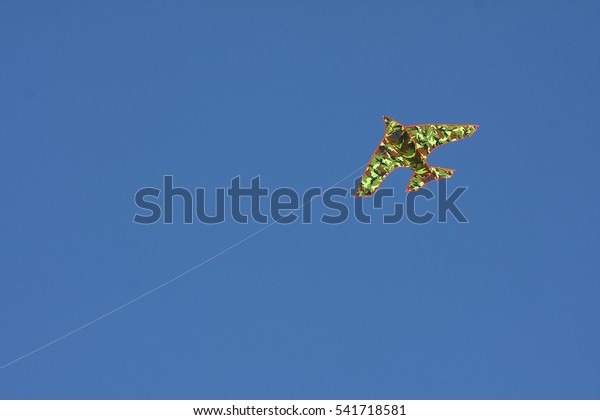 Camouflage kite flying over\
blue sky