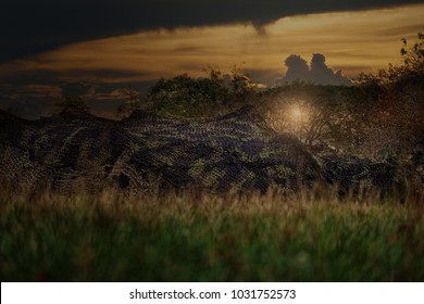 Camouflage Military Army Base Tent In The Field At Sunset
