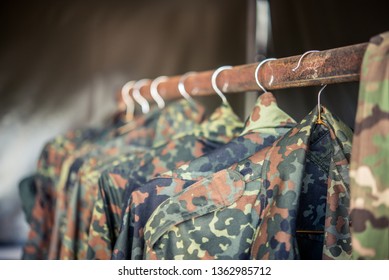 Camouflage military jackets hanging on a rusty clothing rack