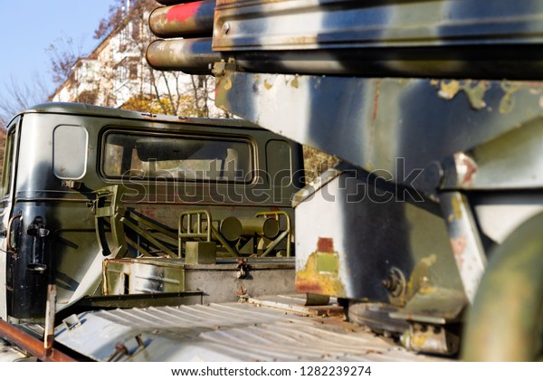 Camouflage military truck with rocket launcher.\
Outdoor military vehicles museum. Armor is damaged at the\
battlefield. Missile firing system on military armored truck close\
up view. Rocket\
launcher.