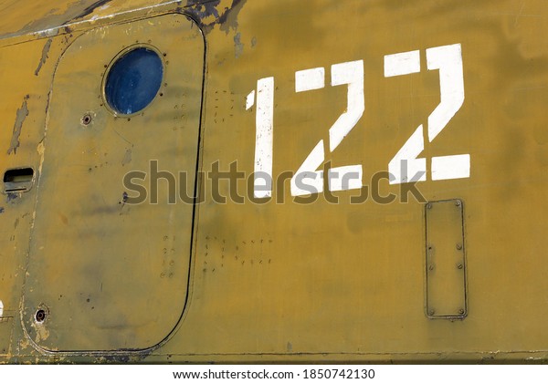 Camouflage side of old military equipment with\
a closed massive door with a round window and number 122 in white\
paint. Army\
background