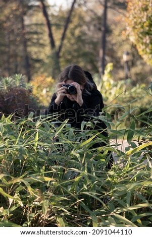 
Camouflage wildlife photographer. A woman is hiding while taking photos in nature. Unrecognizable person.