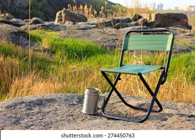 Camp Chair And Thermos Cup On Nature Background